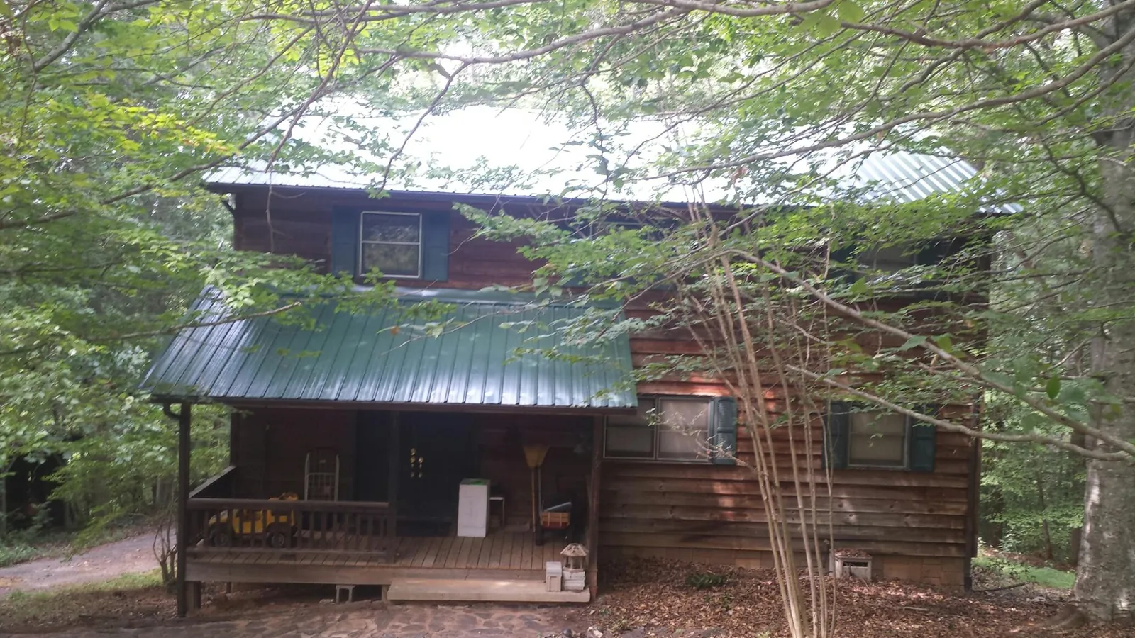 Green metal roof and covered porch on a log cabin in Walsh