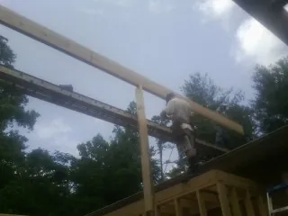 Carpenter setting a ridge beam over a new addition frame — Ice Dam Removal by Roofing Brothers in Walsh