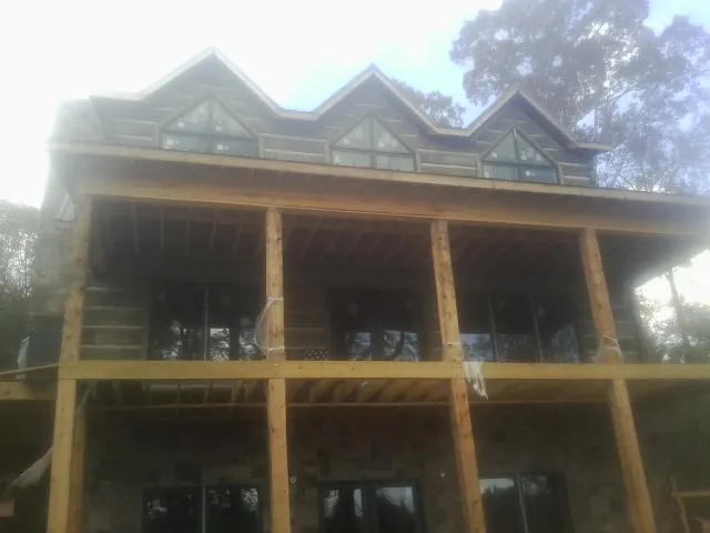 Dormers and porch framing on a large log home under construction — Roof Coating work by our crew in Walsh