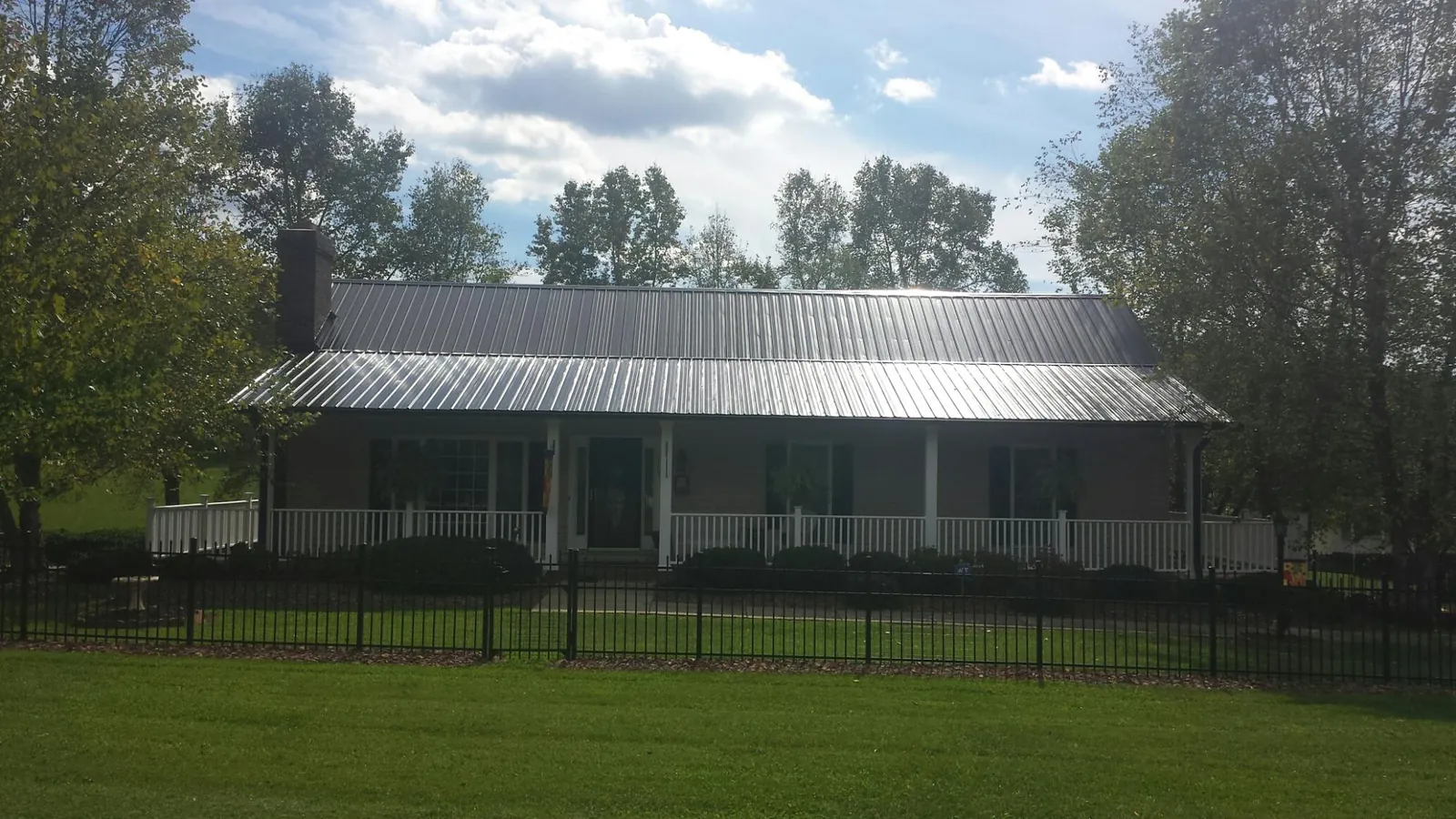 Gray metal roof on a brick ranch with a full width front porch — Gutter Guard Installation work by our crew in Walsh